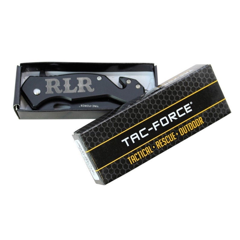 May include: A black pocket knife with a silver blade and a black handle. The knife has a safety feature and a belt clip. The knife is in a black box with the words "TAC-FORCE" and "TACTICAL RESCUE OUTDOOR" printed on it.