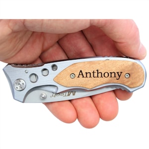 May include: A silver pocket knife with a wood handle. The handle is engraved with the name "Anthony".
