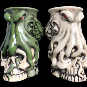 May include: Two ceramic skull mugs with octopus heads. One mug is green and the other is white.