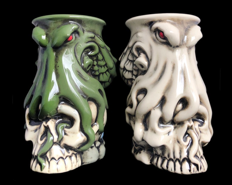 May include: Two ceramic skull mugs with octopus heads. One mug is green and the other is white.