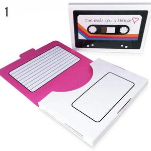 May include: A pink and white card shaped like a cassette tape with the text "I've made you a Mixtape" and a red heart. The card has a flap that opens to reveal a blank space for writing a message.