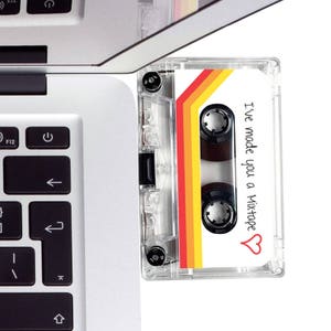 May include: A clear cassette tape with a retro design of red, orange, and yellow stripes. The tape has the text "I've made you a Mixtape" with a heart symbol. The cassette is next to a laptop keyboard.