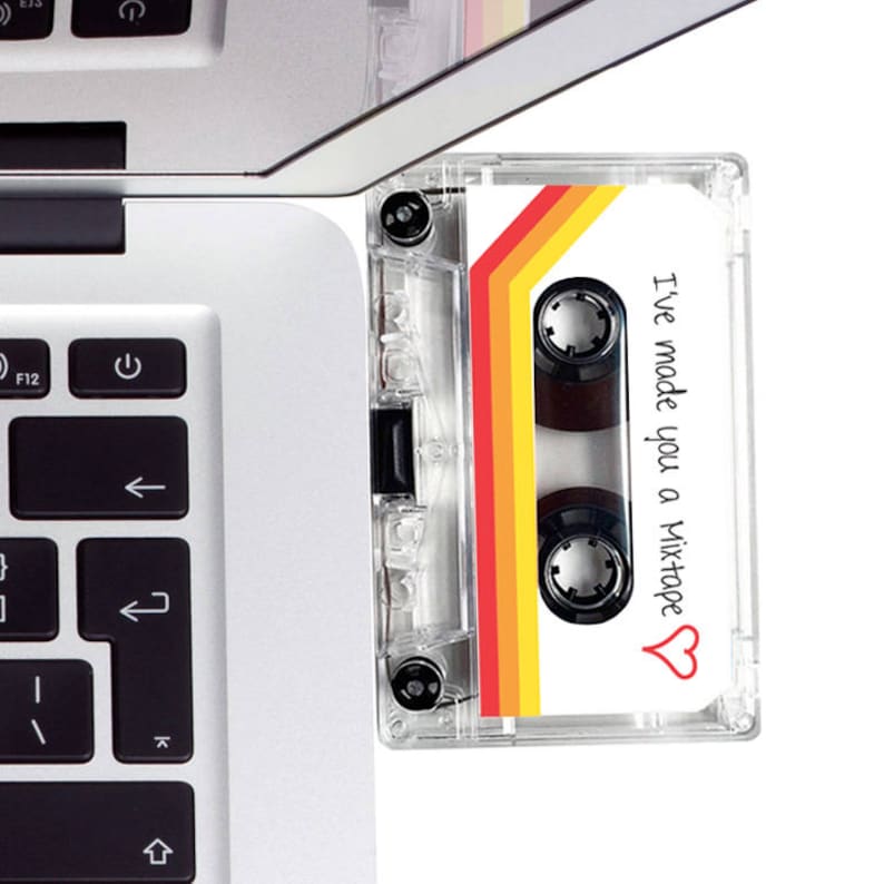 May include: A clear cassette tape with a retro design of red, orange, and yellow stripes. The tape has the text "I've made you a Mixtape" with a heart symbol. The cassette is next to a laptop keyboard.