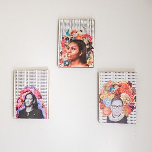 May include: Three framed art prints featuring portraits of prominent women with floral accents. The prints are hung on a white wall.