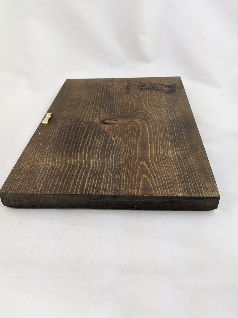 May include: A dark brown wooden sign with a gold metal hanger. The sign has a light brown wood grain pattern and the text "Established 1987" is engraved on the top right corner.