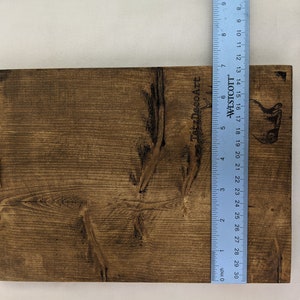 May include: A dark brown wooden sign with a light brown wood grain pattern. The sign is 30 inches long and has a small wooden peg on the left side. The text "TatzDecoArt" is printed on the right side of the sign.