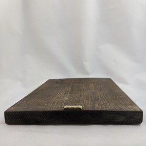 May include: A dark brown wooden sign with a gold metal hanging hook on the bottom edge.