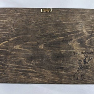 May include: A dark brown wooden sign with a black and white illustration of a person riding a deer. The text "TatzDecoArt" is printed on the sign.