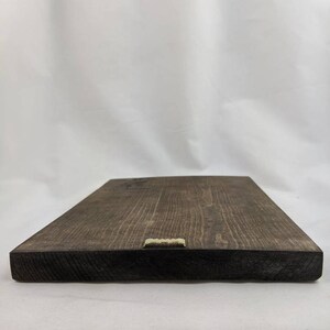 May include: A dark brown wooden sign with a gold metal hanging hook on the bottom edge.