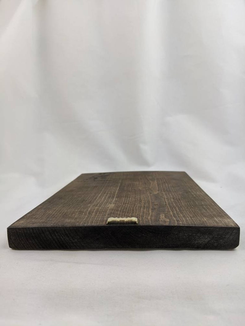 May include: A dark brown wooden sign with a gold metal hanging hook on the bottom edge.