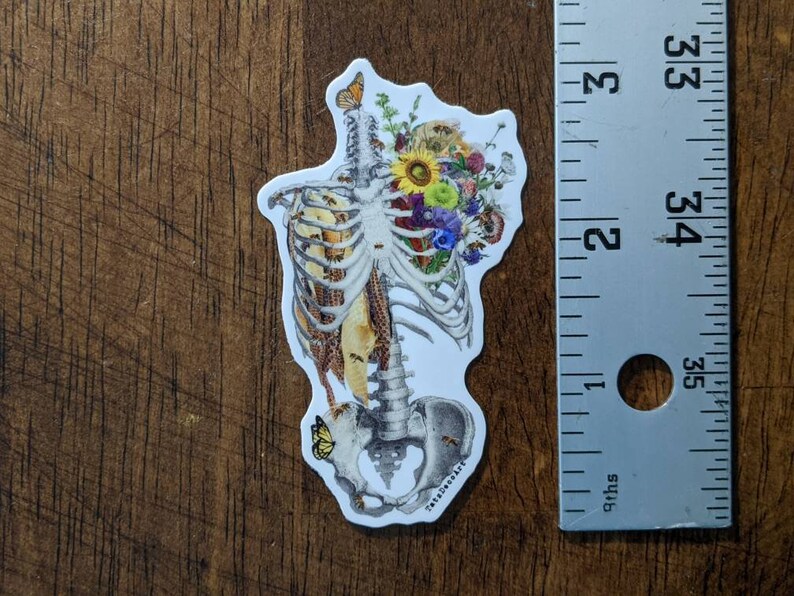 May include: A sticker featuring a detailed anatomical illustration of a human ribcage with a bouquet of colorful flowers and butterflies. The flowers are a mix of yellow, red, pink, and blue.