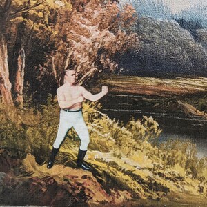 May include: A painting of a man in a boxing stance, wearing white pants and black boots. He is standing on a rocky hill in a forest setting with a river in the background.