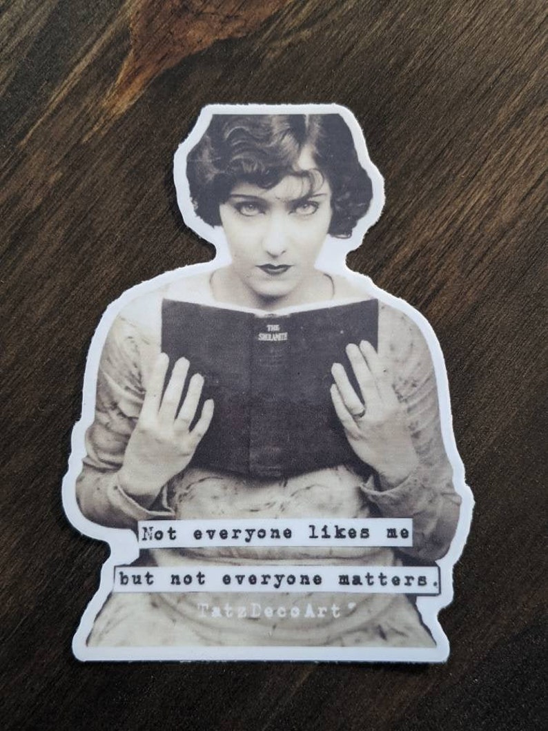 Pu&ograve; includere: Foto in bianco e nero di una donna che legge un libro. Il testo sul libro dice "The Silence". La didascalia sotto l'immagine dice "Not everyone likes me but not everyone matters. TateDecsArt".