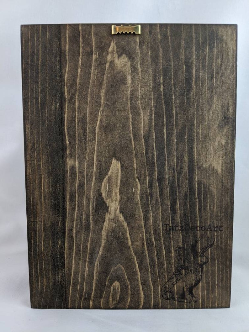 May include: A dark brown wooden sign with a hanging hook on the top. The sign has a black and white logo with the text "TalzDecoArt" and a stylized image of a deer.