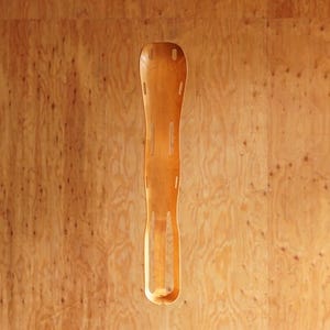 May include: A light-colored wooden ski, with a curved design and cut-out sections. The ski is made of a light-colored wood and has a smooth finish. The ski is designed for use in the snow.