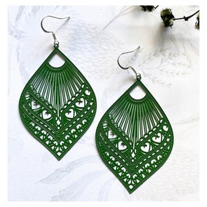 May include: A pair of green dangle earrings with a delicate, intricate design. The earrings are made of metal and have a teardrop shape.