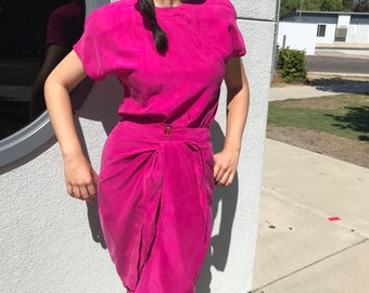 May include: A hot pink two-piece outfit with a short-sleeved top and a wrap skirt.