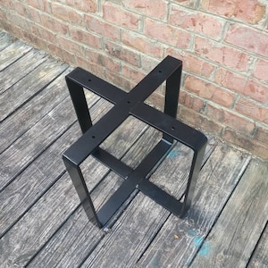 May include: Black metal table base with a square top and four legs. The base is made of sturdy metal and has a simple, modern design.