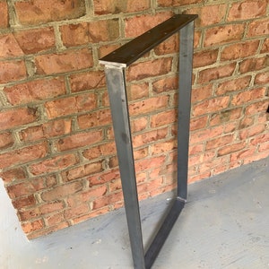 May include: A metal table leg with a rectangular frame. The leg is made of steel and has a dark grey finish.