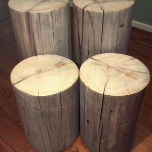 May include: Four rustic wooden stools with a natural wood finish. The stools are made from tree trunks and have a rough, weathered look.