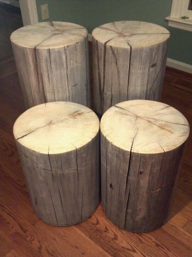 May include: Four rustic wooden stools with a natural wood finish. The stools are made from tree trunks and have a rough, weathered look.