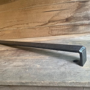May include: A black metal shelf bracket with a 90-degree angle and a flat surface. The bracket is made of sturdy metal and is designed to support shelves.