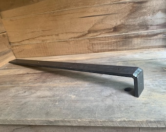May include: A black metal shelf bracket with a 90-degree angle and a flat surface. The bracket is made of sturdy metal and is designed to support shelves.