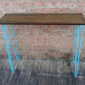 May include: A wooden console table with a dark brown top and four hairpin legs painted a bright turquoise blue.