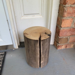 May include: A rustic wooden stool made from a tree trunk, with a natural wood finish and a crack down the center.