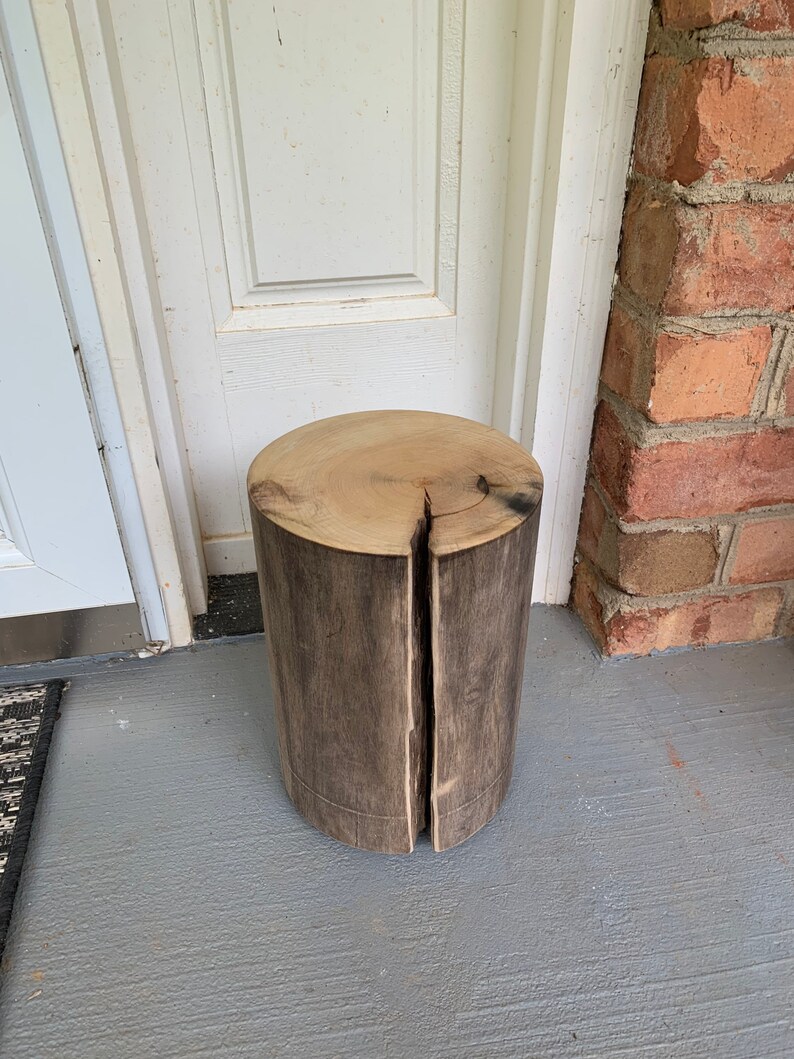 May include: A rustic wooden stool made from a tree trunk, with a natural wood finish and a crack down the center.