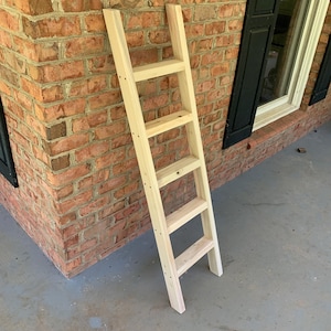 May include: A wooden ladder with five steps, leaning against a brick wall. The ladder is made of unfinished wood and has a natural color.