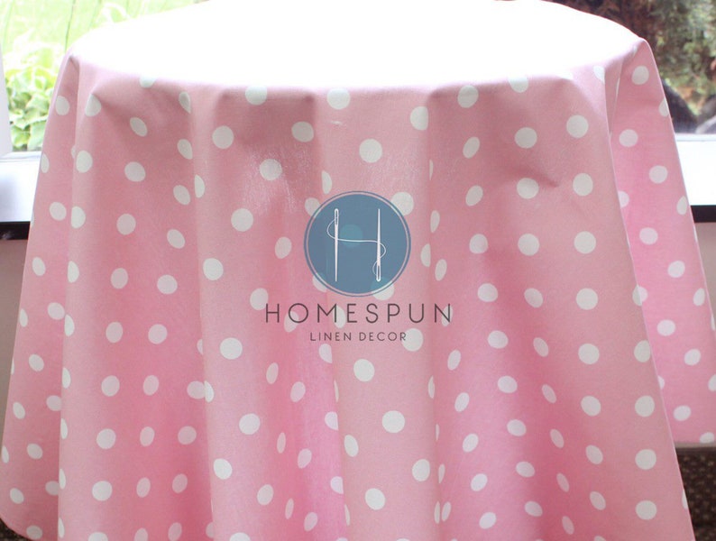 Peut inclure: Nappe rose &agrave; pois blancs. La nappe est en lin et porte l'inscription "HOMESPUN LINEN DECOR".