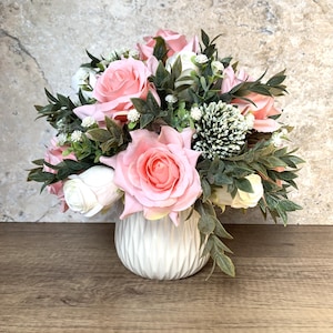 Traditionelles künstliches Blumengesteck mit rosa Rosen in einer weißen keramischen Vase