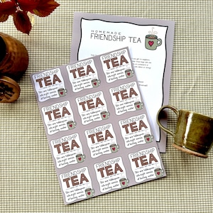 Könnte beinhalten: Ein Blatt braunes Papier mit 12 quadratischen Etiketten, auf denen "Friendship Tea" mit einem kleinen Teetassen-Symbol steht. Die Etiketten sind mit der Anleitung "Stir one tablespoon into eight ounces of boiling water" bedruckt.