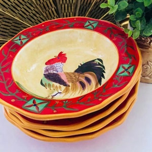 Puede incluir: Un juego de cuatro cuencos de cerámica con un borde rojo y una base amarilla. Los cuencos presentan un diseño pintado a mano de un gallo con una cresta roja y una cola colorida. El gallo está rodeado de enredaderas verdes y flores rojas.