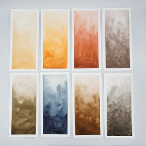 May include: Eight watercolor paintings on paper, each with a different color gradient. The colors are yellow, orange, red, brown, green, blue, tan, and gray.