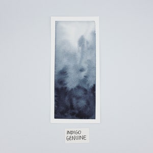 May include: A framed watercolor painting of a gradient of blue shades, from light to dark. The painting is titled "Indigo Genuine".