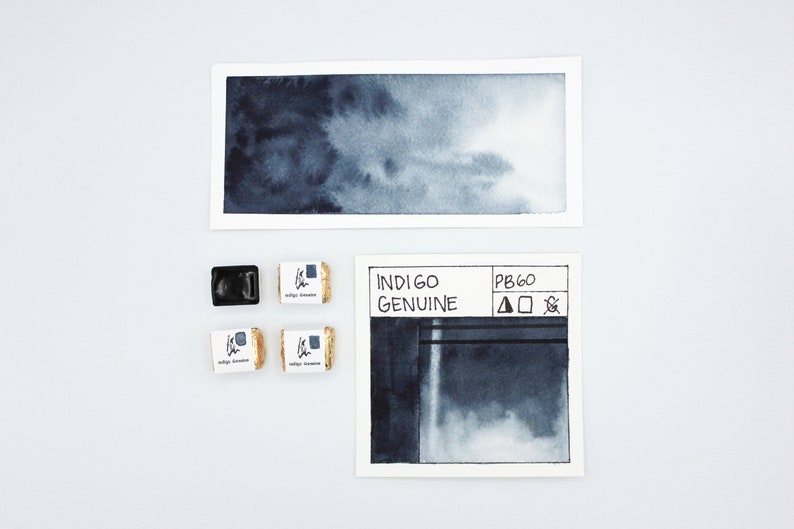 May include: Indigo watercolor paint in a pan with a label that says "Indigo Genuine" and "PB60". The paint is a dark blue color and is shown in a watercolor wash on a white card.