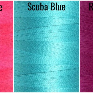 May include: Three spools of thread in different colors: a bright pink spool labeled "Honey Suckle", a turquoise blue spool labeled "Scuba Blue", and a vibrant purple spool labeled "Radiant Orchid".