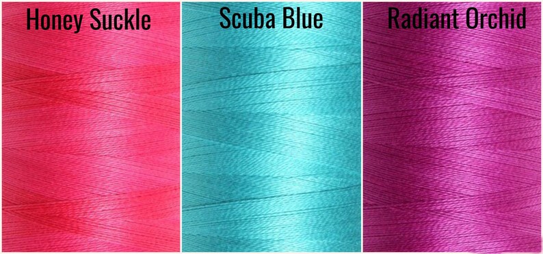 May include: Three spools of thread in different colors: a bright pink spool labeled "Honey Suckle", a turquoise blue spool labeled "Scuba Blue", and a vibrant purple spool labeled "Radiant Orchid".