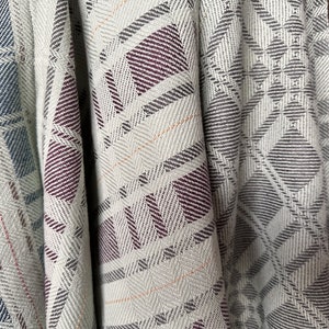 May include: A close-up of a woven fabric with a geometric pattern in shades of green, gray, and burgundy. The fabric has a soft, textured feel and is perfect for a variety of crafting projects.