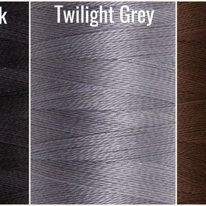 May include: Close-up of three spools of thread in the colors Jet Set Black, Twilight Grey, and Pine Bark.