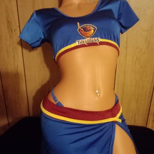 May include: A blue and red costume with the text "Atlanta Thrashers" on the top. The costume is a crop top and a short skirt with a slit on the side.