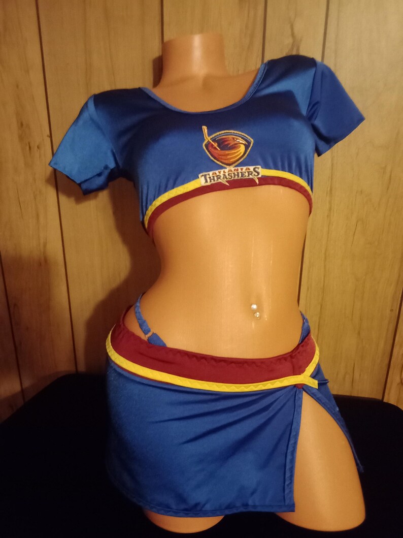 May include: A blue and red costume with the text "Atlanta Thrashers" on the top. The costume is a crop top and a short skirt with a slit on the side.