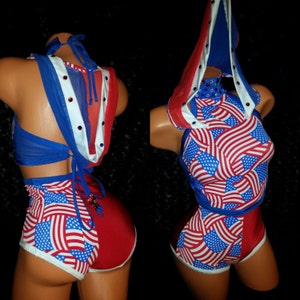 May include: A red, white, and blue two-piece outfit with a halter top and shorts. The top has a hood and the shorts have a white trim. The fabric is printed with an American flag pattern.
