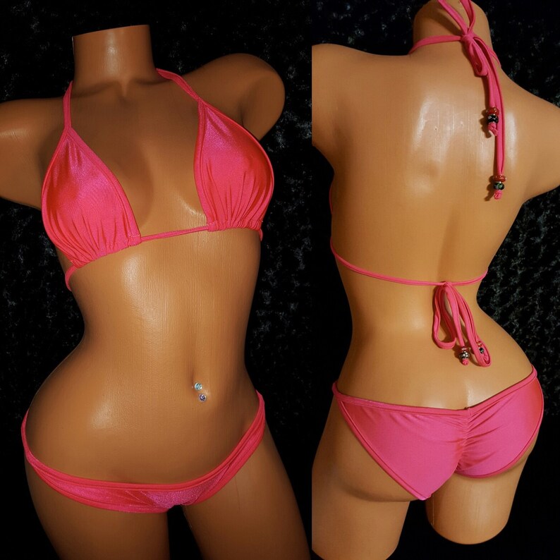 May include: A pink bikini with a halter top and a low-rise bottom. The bikini is made of a shiny, satin-like fabric.