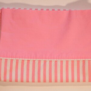 May include: Pink and white striped fabric with a solid pink panel. The fabric is folded in half.