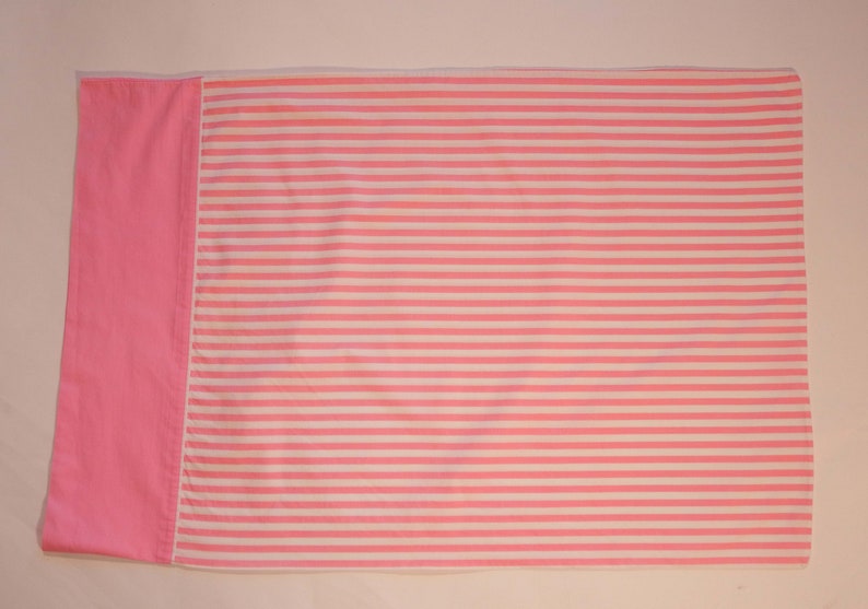 May include: Pink and white striped fabric with a solid pink border. The fabric is folded in half.