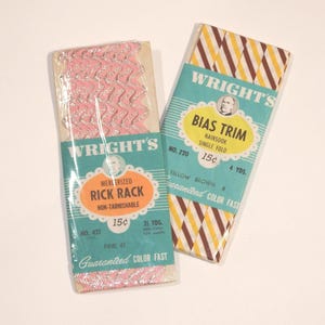 Puede incluir: Dos paquetes vintage de adornos Wright's. Uno contiene rick rack rosa con detalles metálicos plateados, el otro cinta al bies a rayas amarillas, marrones y blancas. Ambos paquetes presentan el logotipo de Wright's e información del producto.