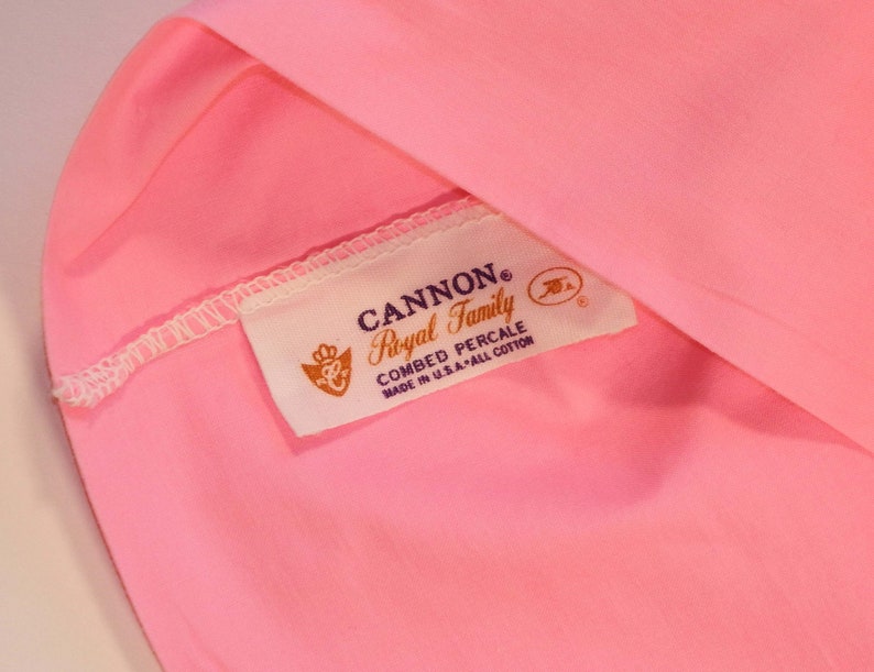 May include: A pink fabric label with the text "CANNON&reg; Royal Family Combed Percale Made in U.S.A. - All Cotton" in black and purple lettering.